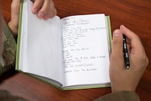An Airman writes down finance-related training notes in his notebook.