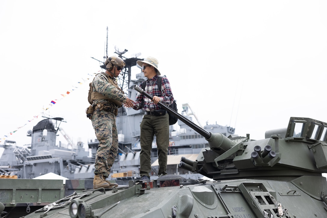 U.S. Marine Corps Lance Cpl. Isaac Rodriguez, left, a light armored reconnaissance vehicle crewman with 3rd Light Armored Reconnaissance Battalion, 1st Marine Division, poses for a photo with a local during Los Angeles Fleet Week in Los Angeles, May 23, 2025.