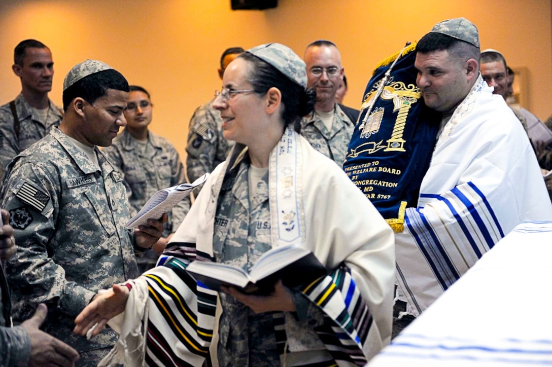 A female U.S. Air Force rabbi walks through a group of worshipers shaking hands.