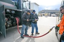 Two men stand by a fuel truck