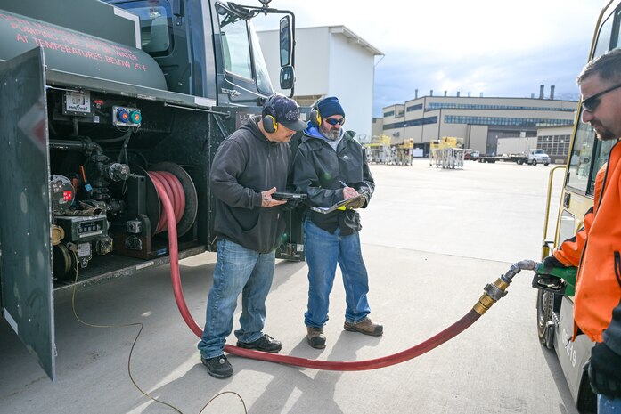 Two men stand by a fuel truck