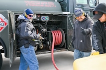 Two men stand by a fuel truck giving a thumbs up