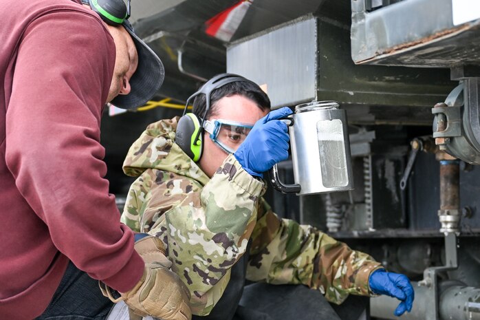 an Airman looks at a fuel sample in a jar