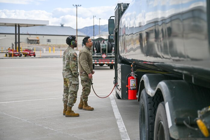 Two Airman stand by a fuel truck