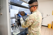 An airman pours a fuel sample into a beaker