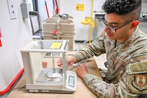 a airman places a white disk into a scale