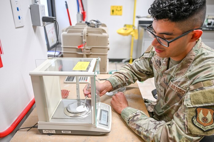 a airman places a white disk into a scale