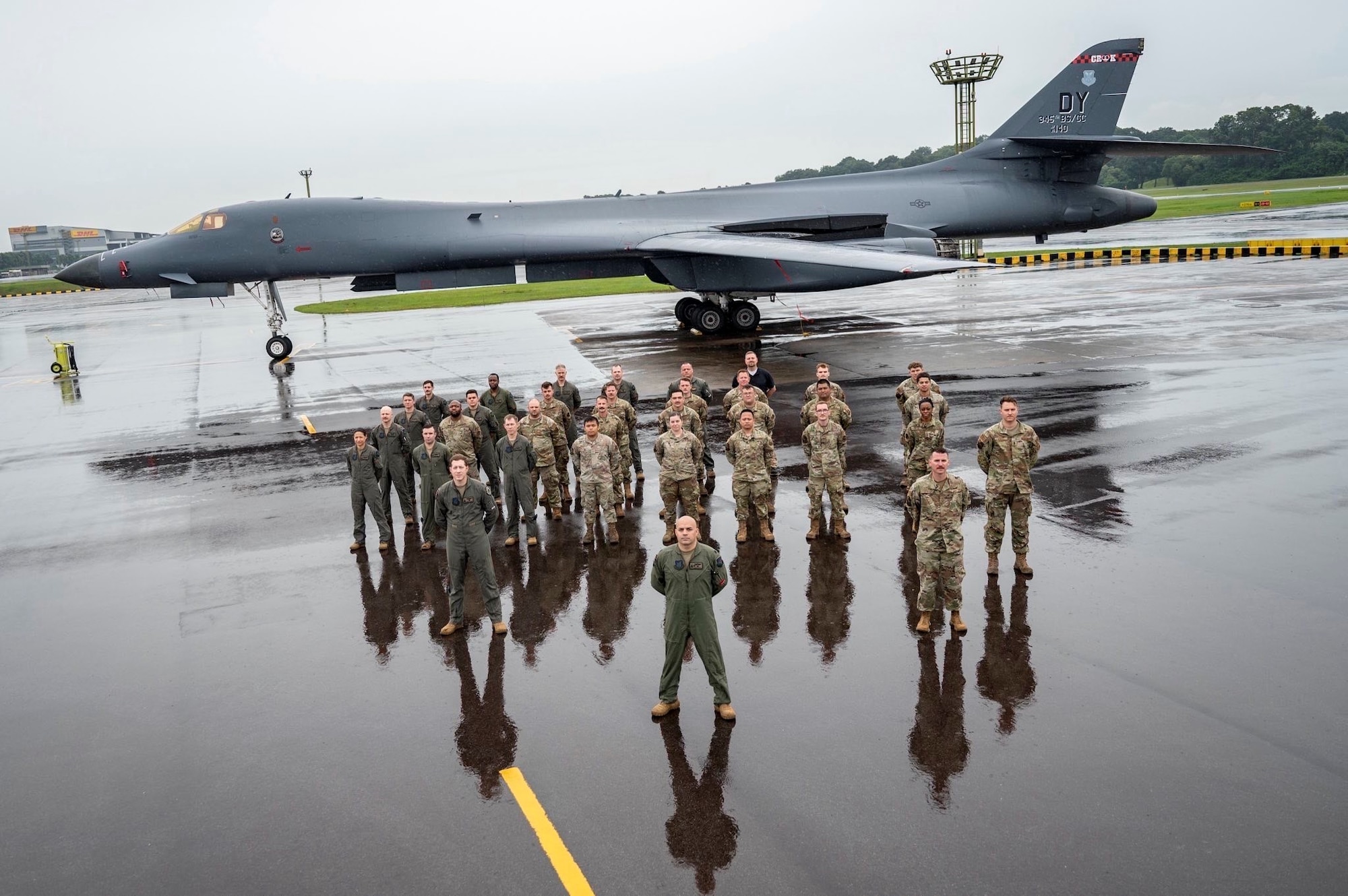 Lt. Col. Eric Alvarez stands squarely in front of his unit with a B-1 jet positioned behind them.