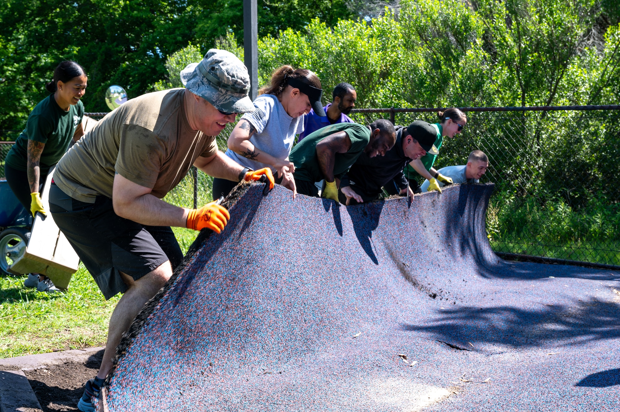 Photo of multiple airmen rolling up outdoor flooring material.