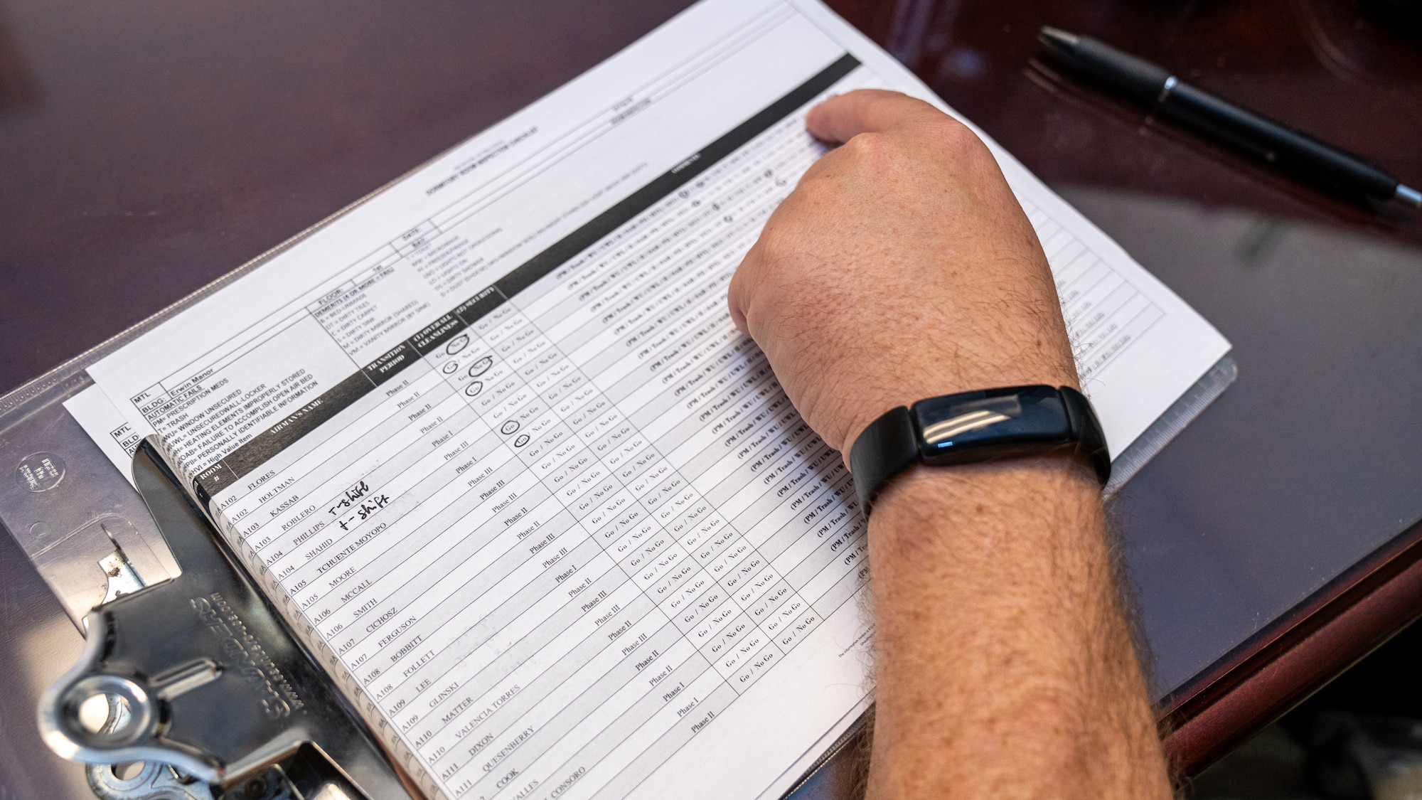 A mans hand checks a white paper printed with room inspection results.