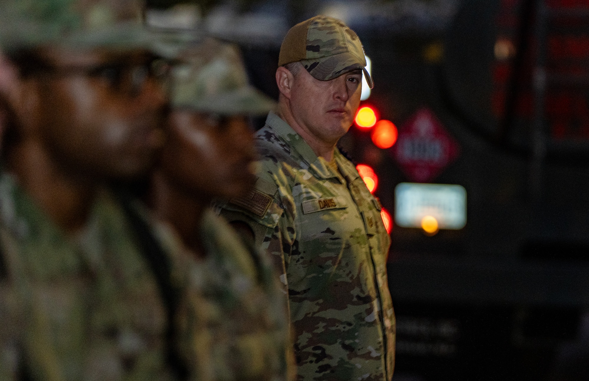 A man in military uniform stands near a group of Air Force trainees inspecting them.