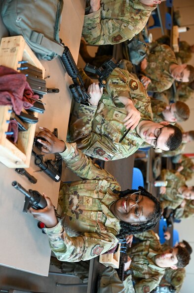 U.S. Air Force Master Sgt. Bryon Mordhorst flight chief and Senior Airman Dominique Henry, contracting specialist from the 5th contracting squadron disassemble the M4 at Minot Air Force Base, May 8th, 2025. Disassembly of the weapons allows Airmen to become more familiar with them, making them more deployment ready. (U.S. Air Force photo by Airman 1st Class Anthony Ramey)