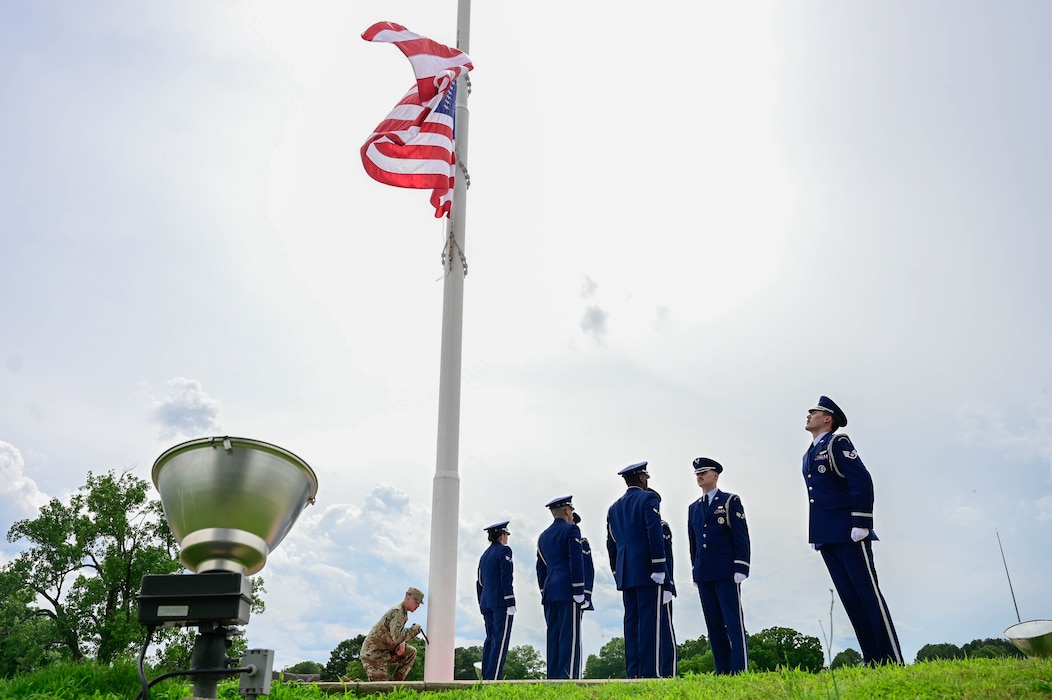 Base Honor Guard Members prepare to secure the flag during a ceremony.