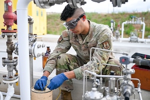 An Airman collects a fuel sample into a jug