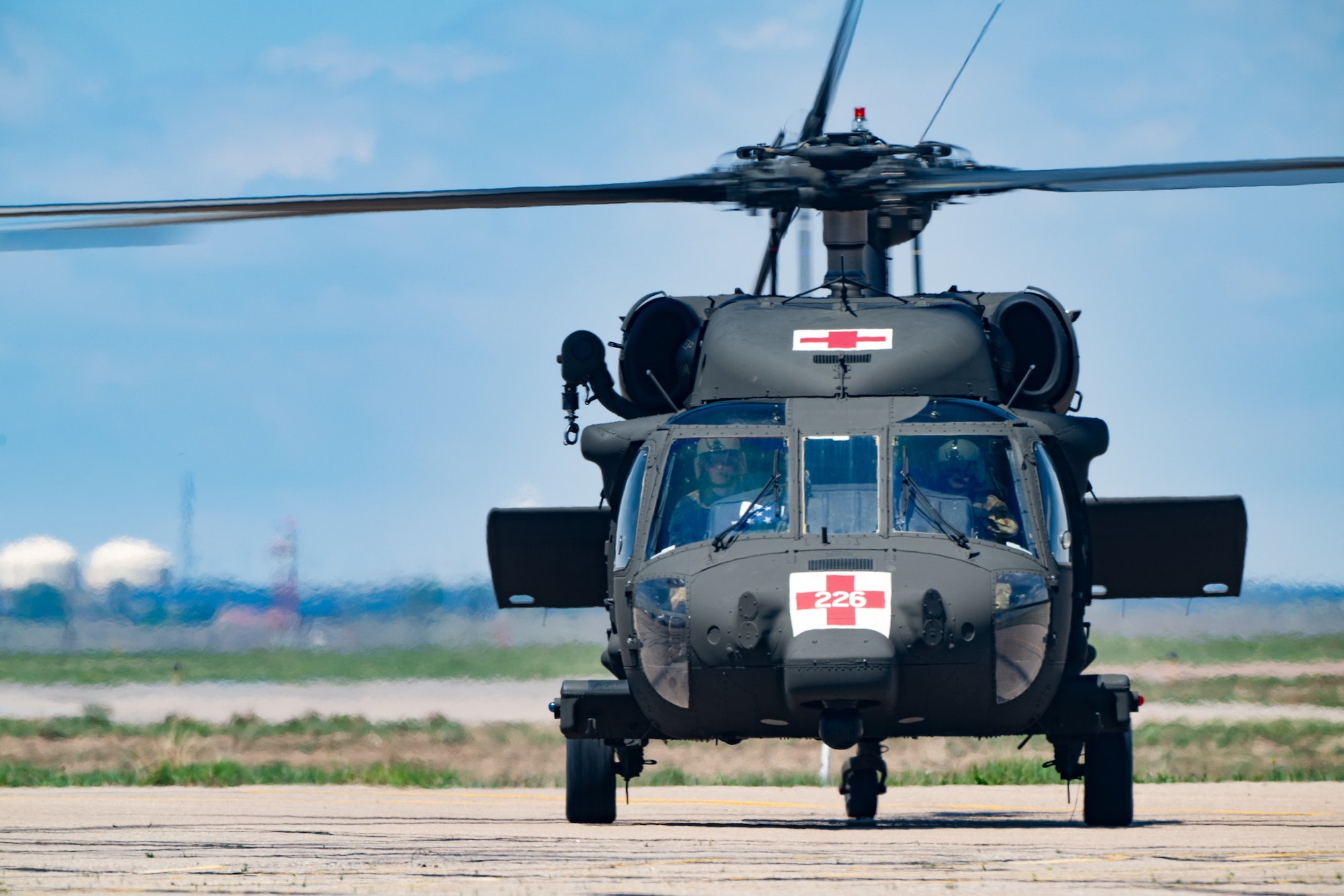 A helicopter with medical cross markings on it taxis at an airport.