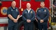 Three people wearing Tobyhanna Army Depot Fire & Emergency Services apparel stand in front of a firetruck and pose for a photo.