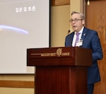 Mr. Todd Pennington (INSS) speaks behind a podium  and presents on Space and Law in Competition and Conflict at the Northeast Asia Operations and International Law Conference, presented by the Korea Tri-Command SJA Office.