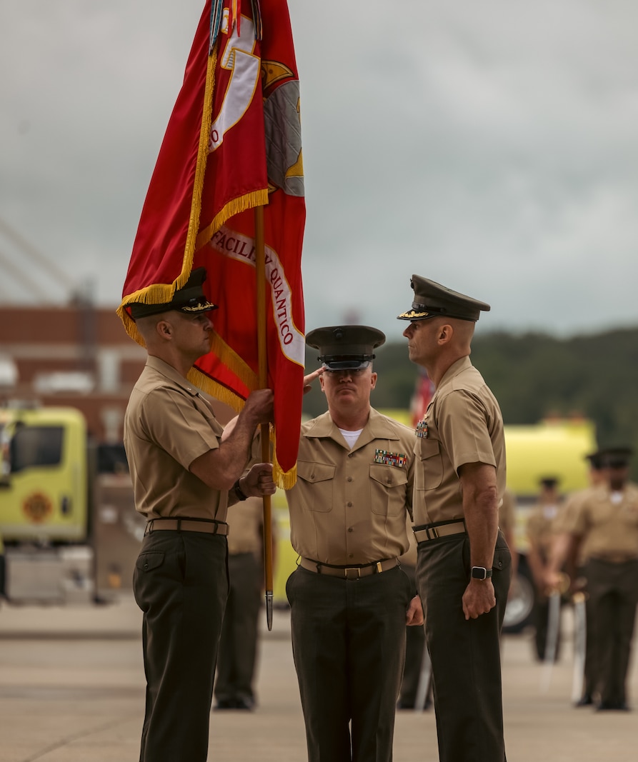 U.S. Marine Corps Lt. Col. Ethan Krumnow, left, incoming commanding officer, Marine Corps Air Facility Quantico, receives the flag from Col. Scott Warman, outgoing commanding officer, MCAF Quantico, during a change of command ceremony at MCAF on Marine Corps Base Quantico, Virginia, May 22, 2025. MCAF operates and maintains the facilities, and provides services and materiel to support the operations of Marine Helicopter Squadron 1 and other transient aircraft as required. (U.S. Marine Corps photo by Lance Cpl. Ethan Miller)