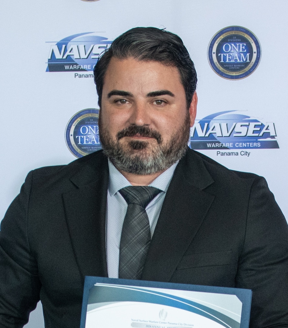 Evan Sarantos, Naval Surface Warfare Center Panama City Division’s Expeditionary Sea Base Command, Control, Communications, Computers, and Intelligence Project lead systems engineer, receives the NSWC PCD FY24 Annual Award for Technical Excellence, March 27. This mission is essential to supporting the Force Behind the Fleet as a crucial element for effective modern warfare in complex and dynamic environments. (U.S. Navy photo by Eddie Green)