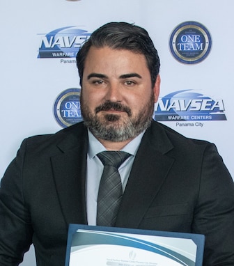 Evan Sarantos, Naval Surface Warfare Center Panama City Division’s Expeditionary Sea Base Command, Control, Communications, Computers, and Intelligence Project lead systems engineer, receives the NSWC PCD FY24 Annual Award for Technical Excellence, March 27. This mission is essential to supporting the Force Behind the Fleet as a crucial element for effective modern warfare in complex and dynamic environments. (U.S. Navy photo by Eddie Green)