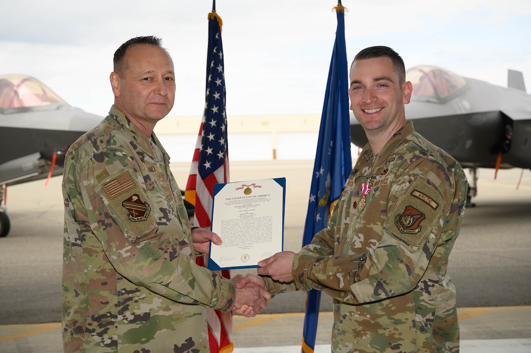 U.S. Air Force Col. Jerry Copeland, 354th Maintenance Group commander, awards Maj. John Ritschard, 356th Fighter Generation Squadron outgoing commander, with the Meritorious Service Medal during a change of command ceremony