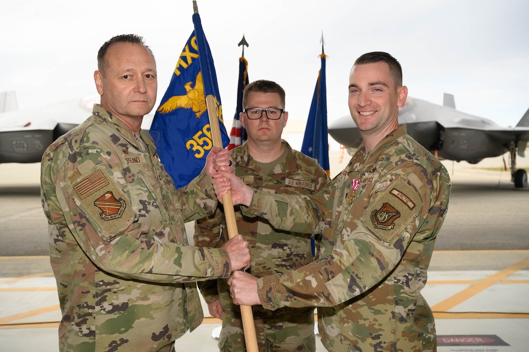 U.S. Air Force Maj. John Ritschard, right, 356th Fighter Generation Squadron outgoing commander, relinquishes command to Col. Jerry Copeland, 354th Maintenance Group commander, during a change of command ceremony