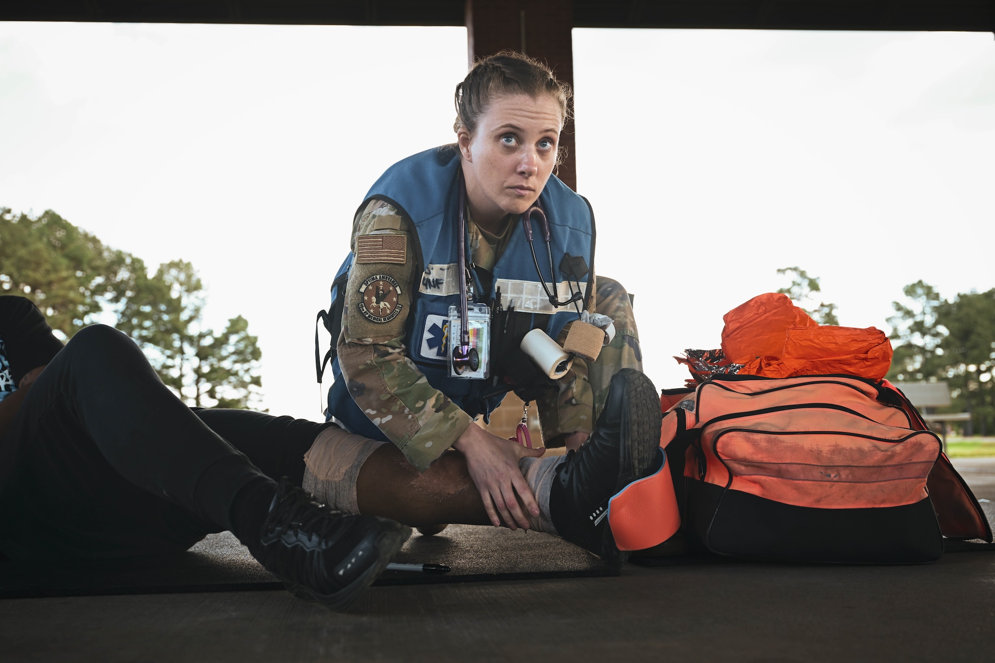 A woman in uniform tends to a simulated patient.