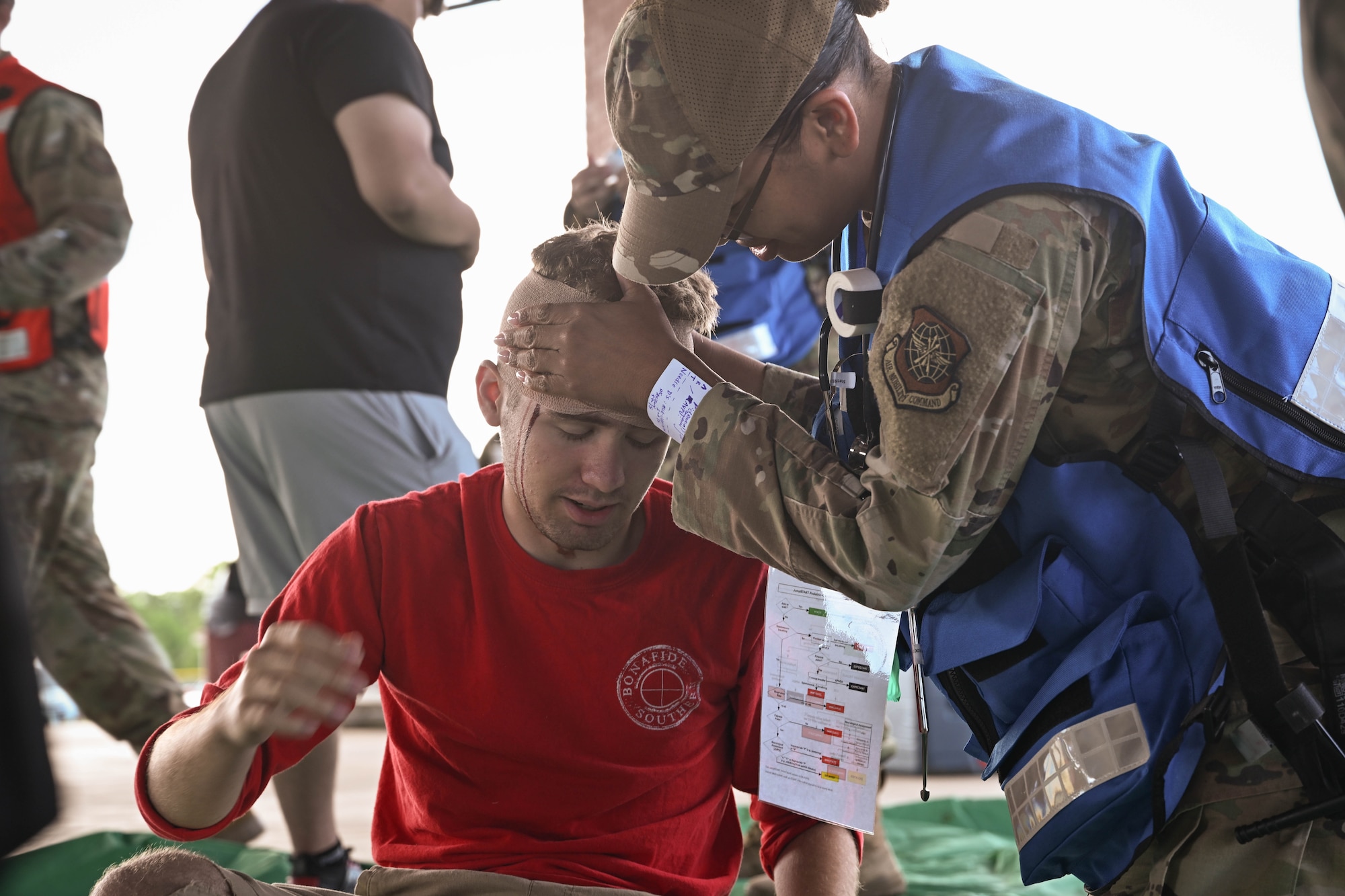 A woman in uniform tends to a simulated patient.