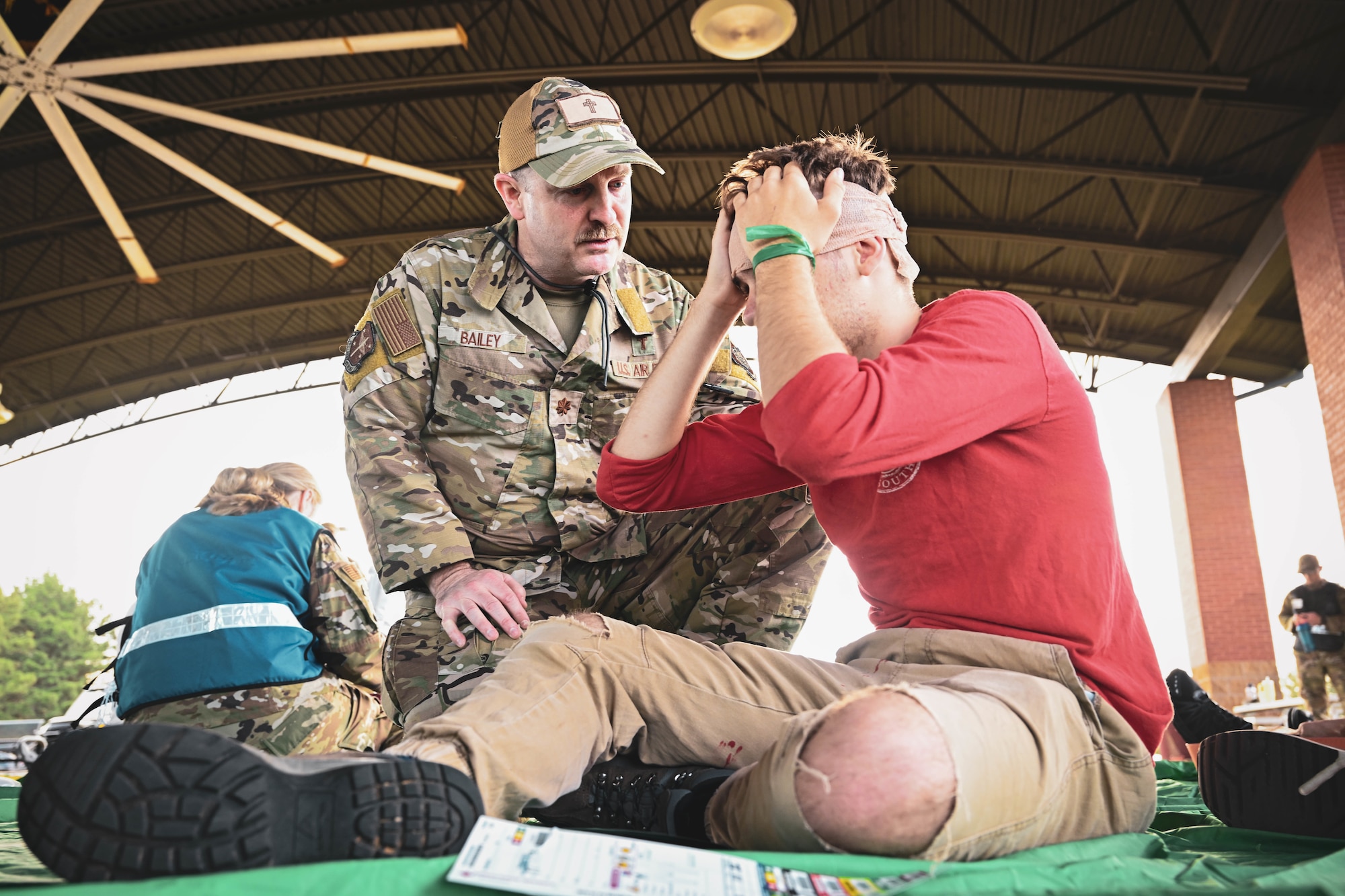 A chaplain in uniform talks to a simulated patient.