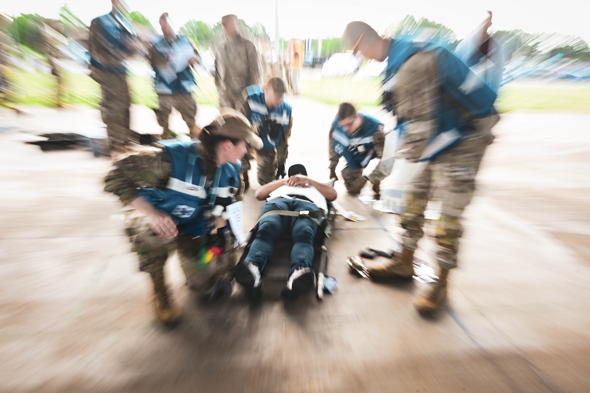 A group of men and women in uniform lift a litter.