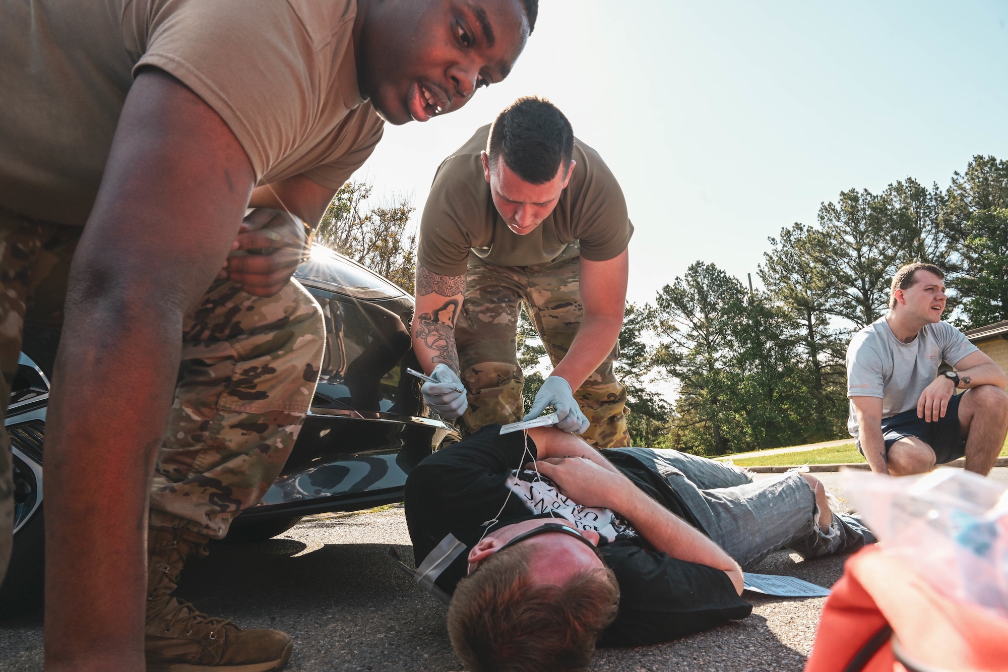 Men in uniform render aid to a simulated patient.