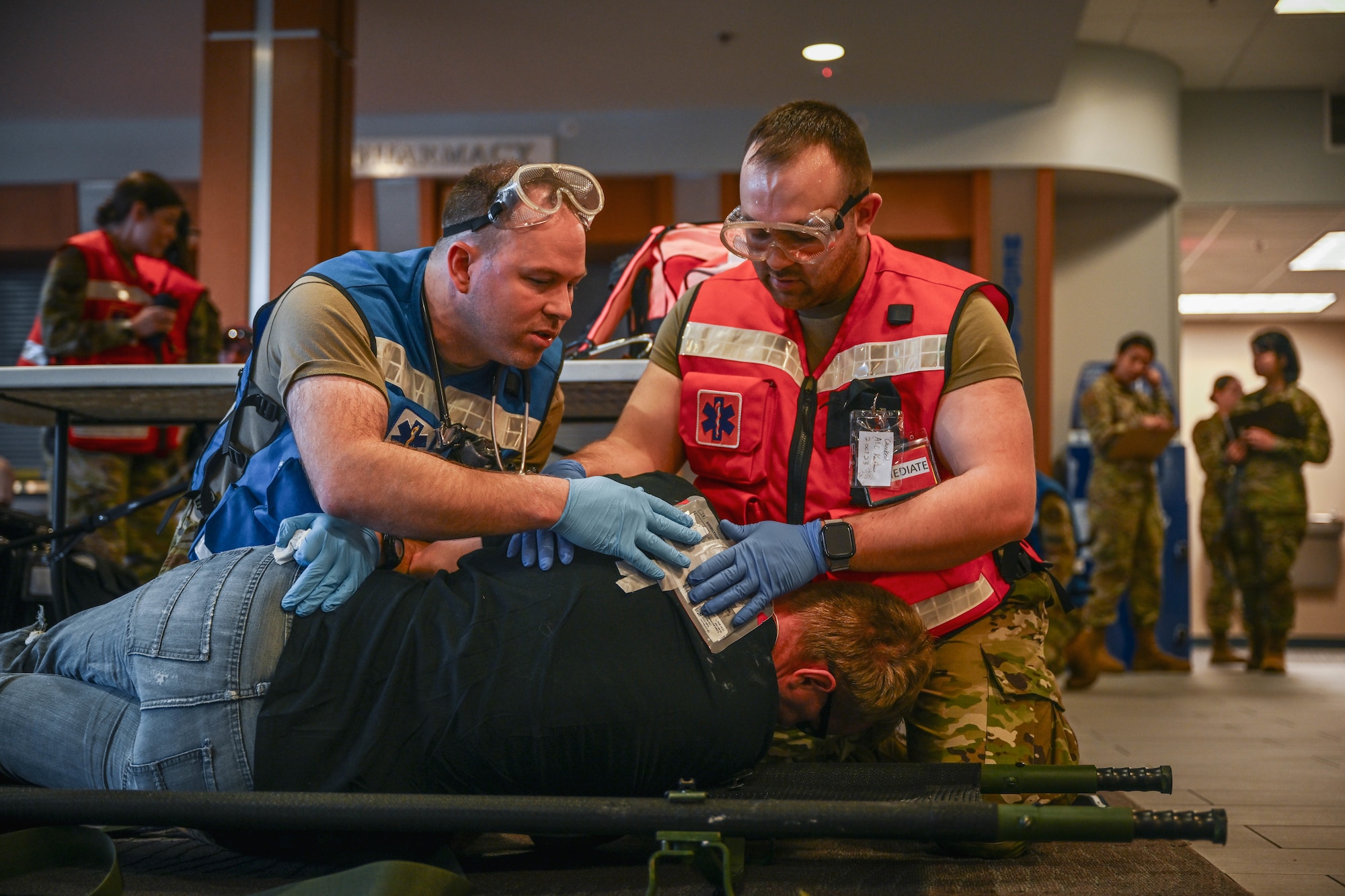 Men in uniform provide aid to a simulated patient.