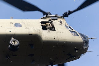 U.S. service member looks out of an army helicopter mid flight