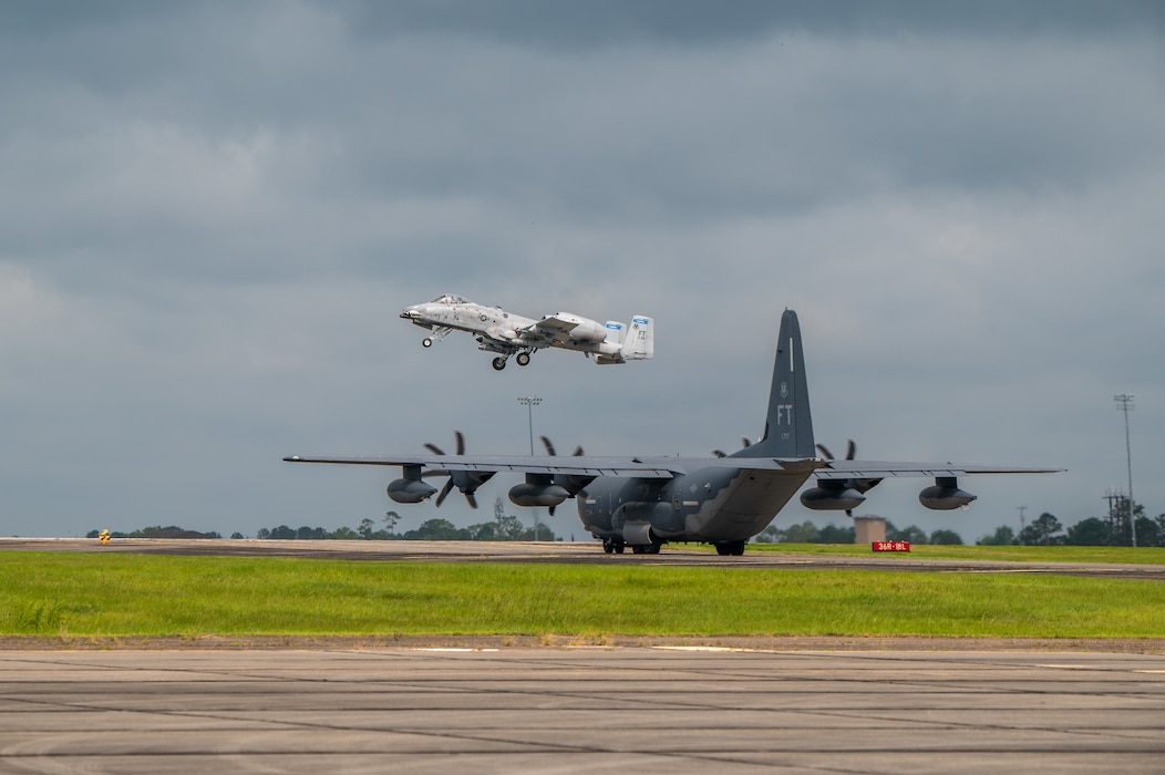 Plane in the foreground stands still, as another plane flies through the air.