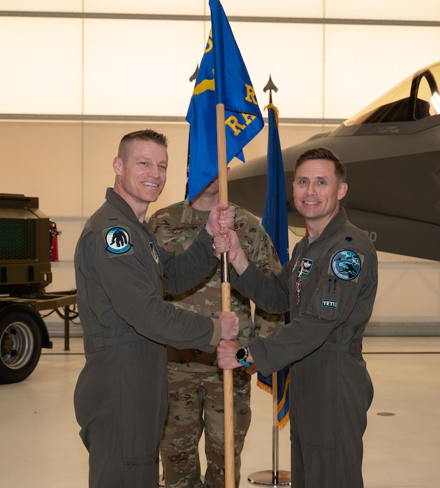 U.S. Air Force Lt. Col. Jay Doerfler, right, 354th Range Squadron outgoing commander, relinquishes the guidon to Col. Curtis Dougherty, 354th Operations Group commander, during a change of command ceremony
