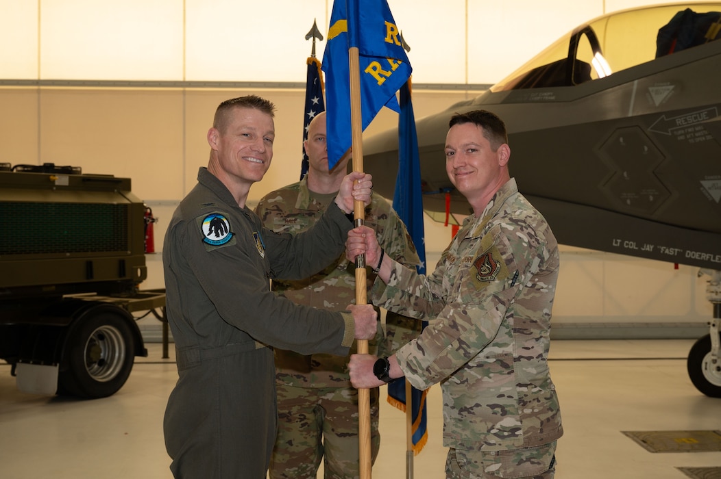 U.S. Air Force Col. Curtis Dougherty, left, 354th Operations Group commander, passes the guidon to Maj. Joseph Hamilton, 354th Range Squadron incoming commander, during a change of command ceremony