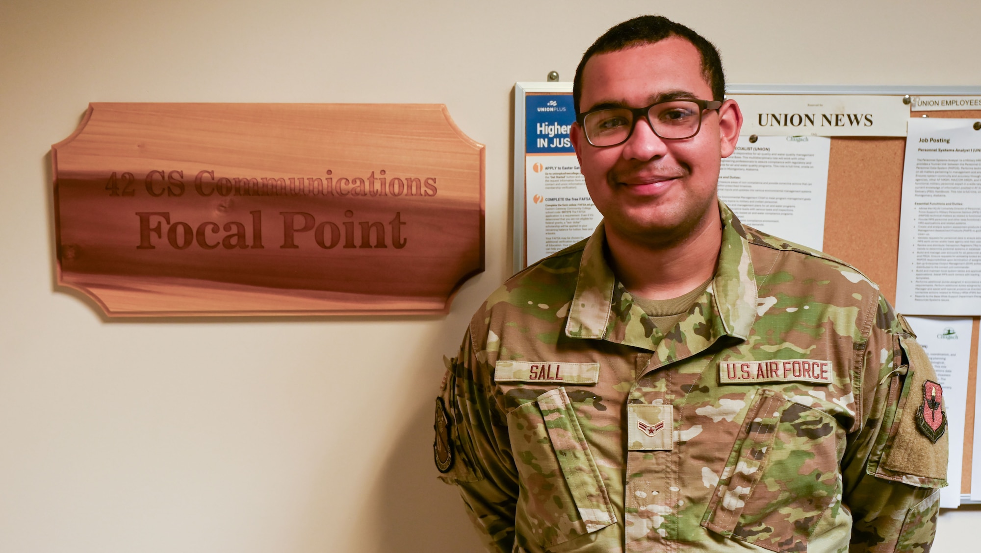 U.S. Air Force Airman 1st Class Mohamed Sall, 42nd Communications Squadron communications focal point technician, poses for a photo in front of the 42nd CS communications focal point plaque at Maxwell Air Force Base, Alabama May 20, 2025.