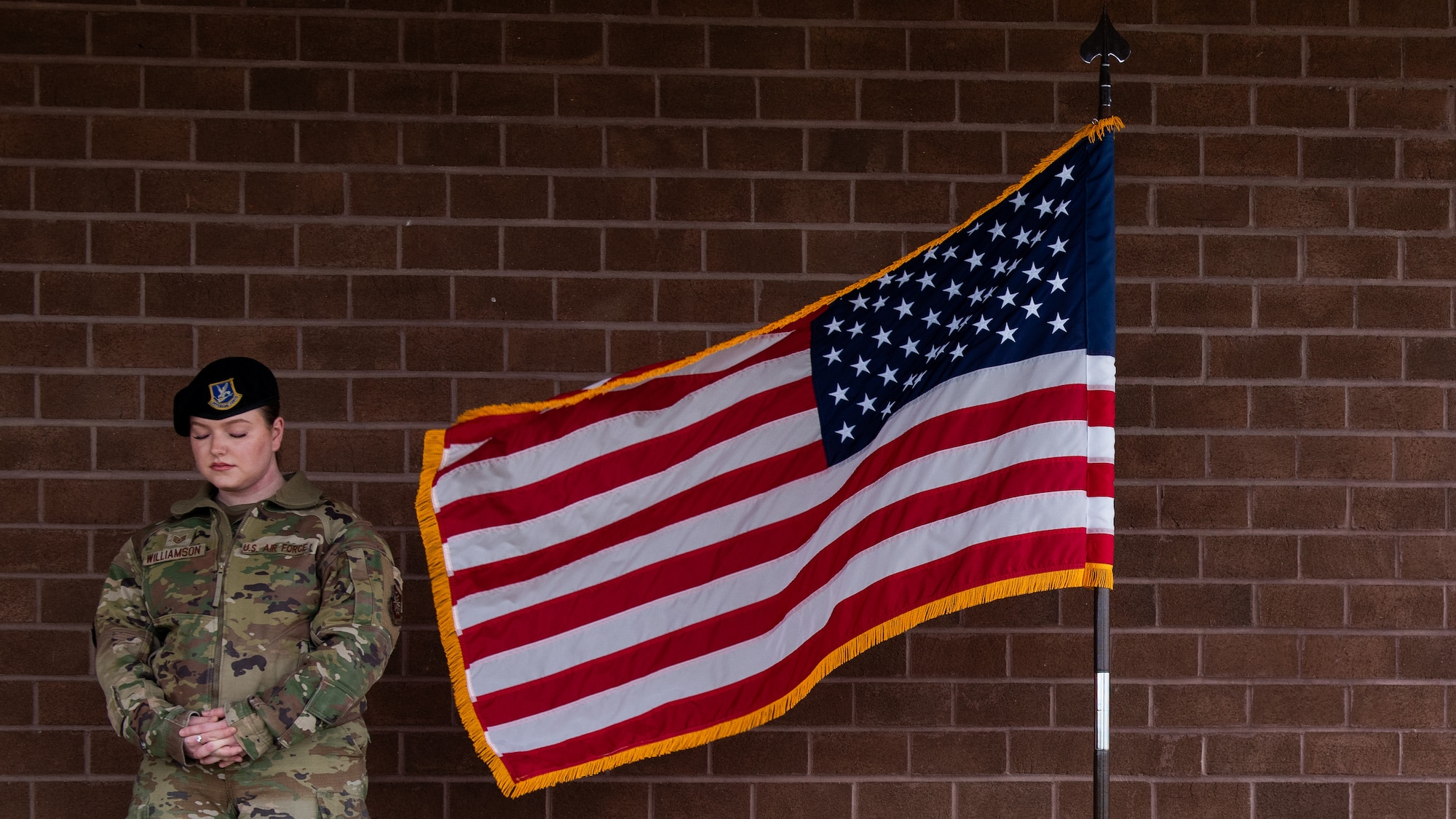 Airman bows heard during benediction with flag waving