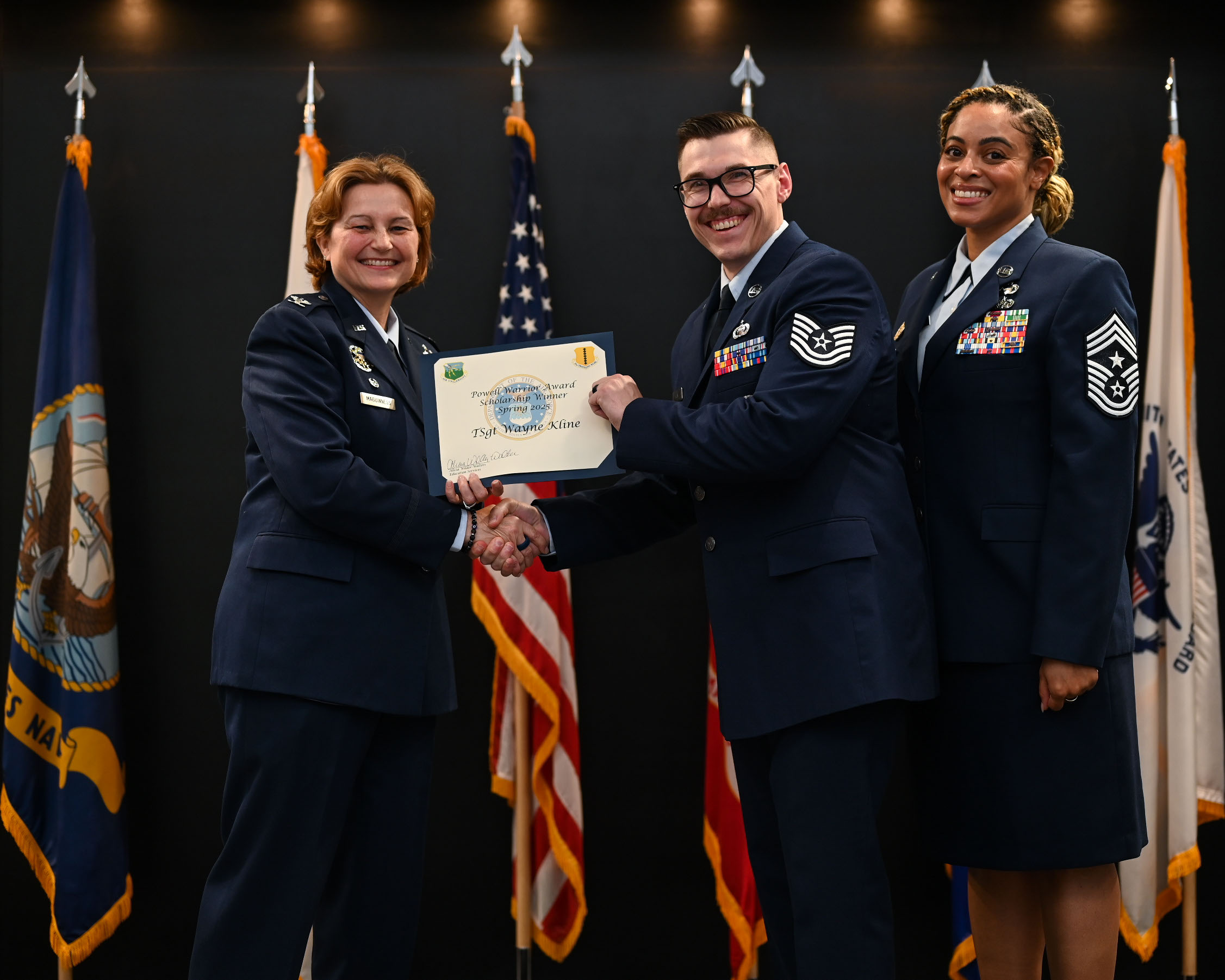 U.S. Air Force Tech. Wayne Kline, 17th Training Group executive, accepts the Powell Warrior Award Scholarship from Col. Angelina Mauginness, 17th Training Wing commander, and Chief Master Sgt. Khamillia Washington, 17th Training Wing command chief, during Goodfellow’s Community College of the Air Force Fall ‘24 and Spring ‘25 Graduation Ceremony at the Powell Event Center, Goodfellow Air Force Base, Texas, May 21, 2025. The award is presented to those who choose to continue their education. (U.S. Air Force photo by Senior Airman Evelyn J. D’Errico)