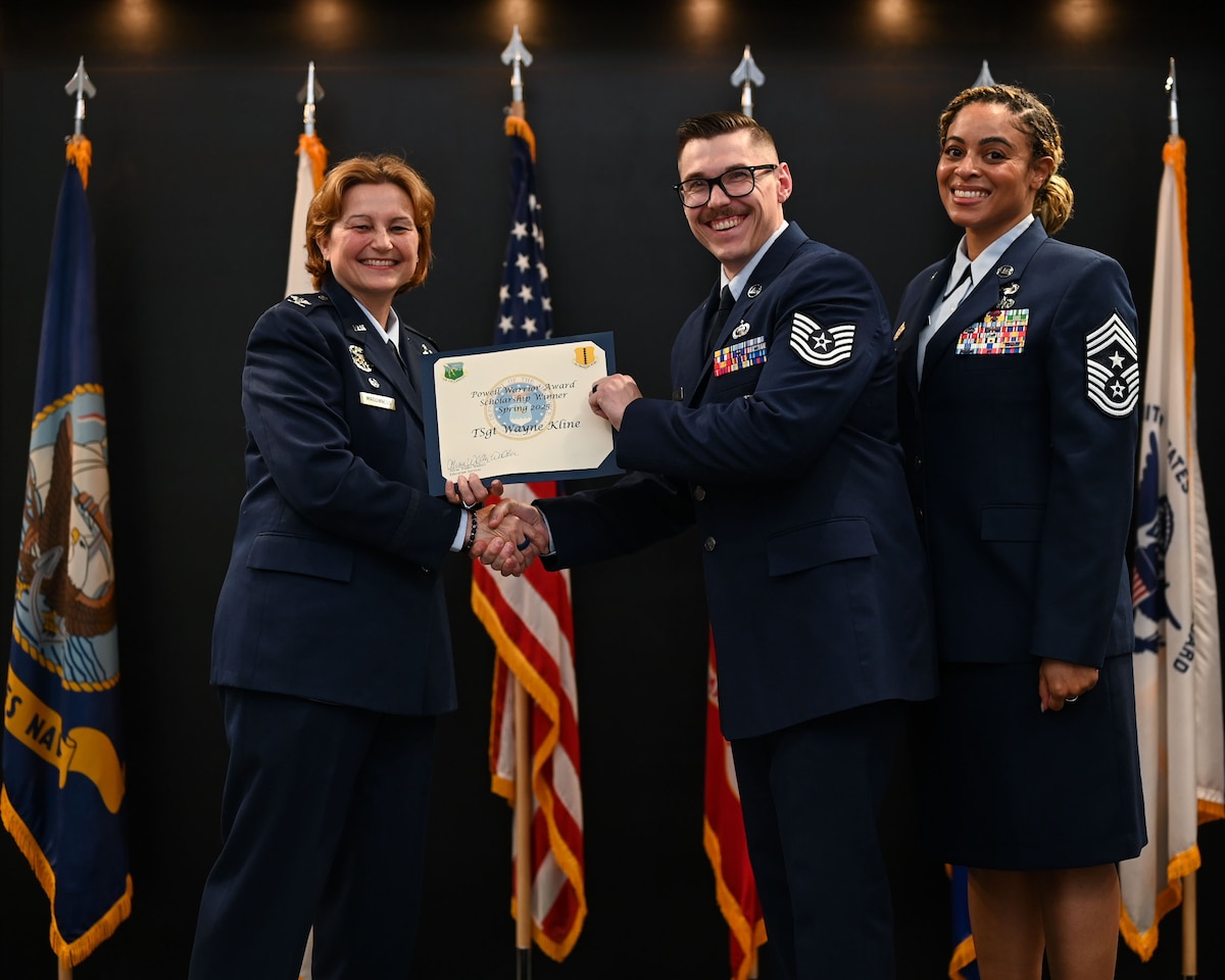 U.S. Air Force Tech. Wayne Kline, 17th Training Group executive, accepts the Powell Warrior Award Scholarship from Col. Angelina Mauginness, 17th Training Wing commander, and Chief Master Sgt. Khamillia Washington, 17th Training Wing command chief, during Goodfellow’s Community College of the Air Force Fall ‘24 and Spring ‘25 Graduation Ceremony at the Powell Event Center, Goodfellow Air Force Base, Texas, May 21, 2025. The award is presented to those who choose to continue their education. (U.S. Air Force photo by Senior Airman Evelyn J. D’Errico)