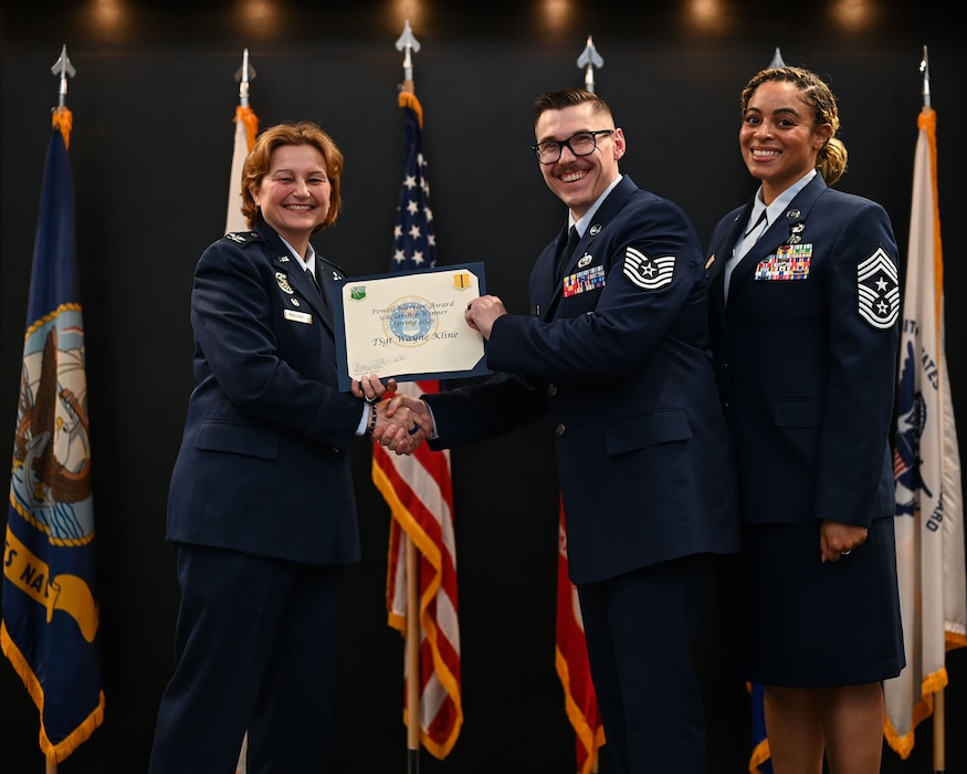 U.S. Air Force Tech. Wayne Kline, 17th Training Group executive, accepts the Powell Warrior Award Scholarship from Col. Angelina Mauginness, 17th Training Wing commander, and Chief Master Sgt. Khamillia Washington, 17th Training Wing command chief, during Goodfellow’s Community College of the Air Force Fall ‘24 and Spring ‘25 Graduation Ceremony at the Powell Event Center, Goodfellow Air Force Base, Texas, May 21, 2025. The award is presented to those who choose to continue their education. (U.S. Air Force photo by Senior Airman Evelyn J. D’Errico)
