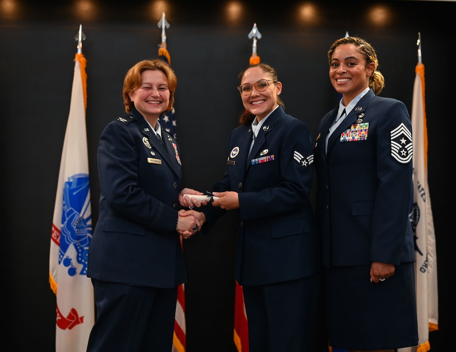 U.S. Air Force Senior Airman Mallory Creech, 315th Training Squadron instructor, receives her degree from Col. Angelina Maguinness, 17th Training Wing commander, and Chief Master Sgt. Khamillia Washington, 17th TRW command chief, as she walks across the stage during Goodfellow’s Community College of the Air Force Fall ‘24 and Spring ‘25 Graduation Ceremony at the Powell Event Center, Goodfellow Air Force Base, Texas, May 21, 2025. The 42 graduates gained their associate's degree through hard work and dedication. (U.S. Air Force photo by Senior Airman Evelyn J. D’Errico)