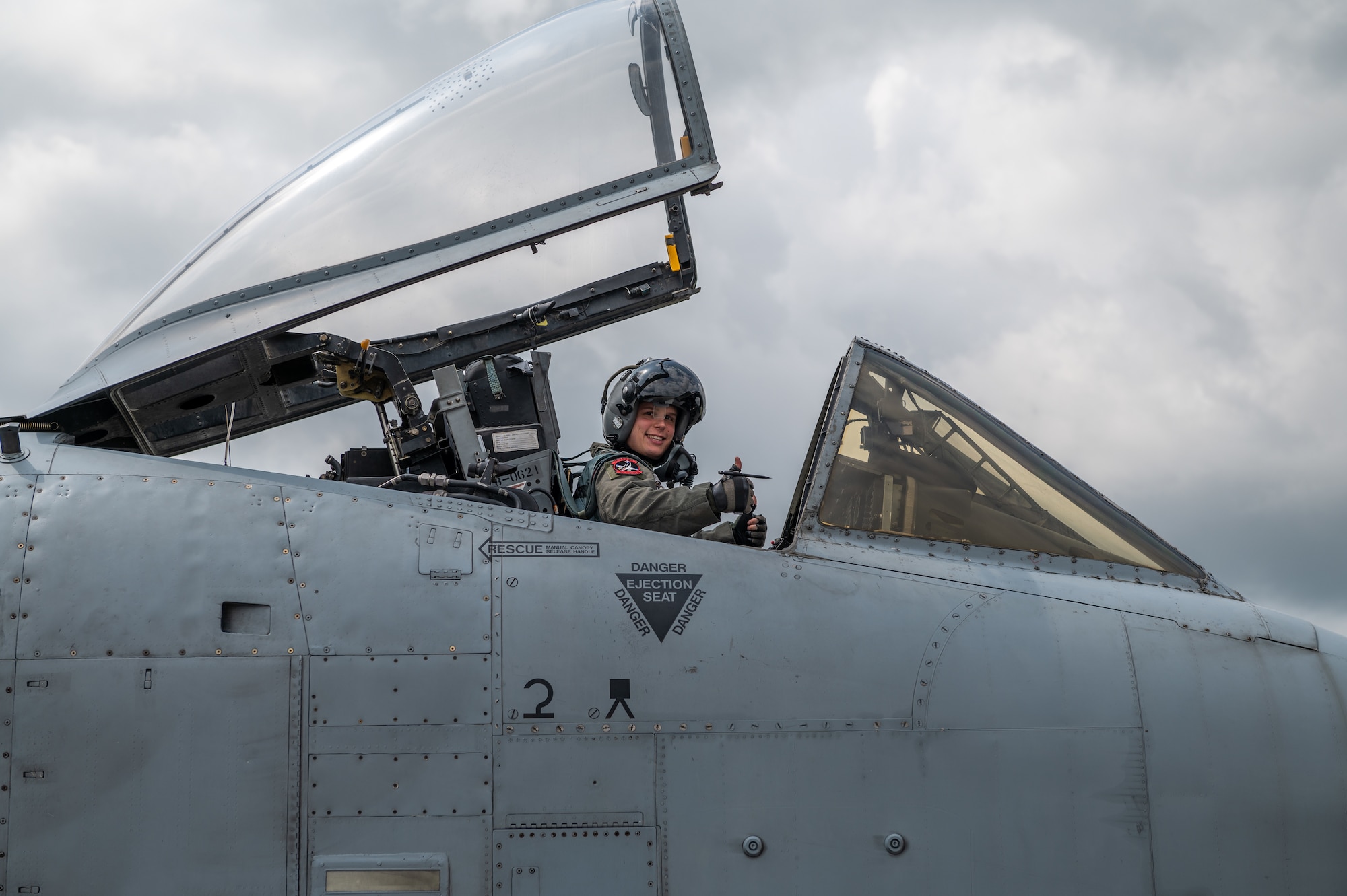 Pilot sits in plane, smiling at the camera with a thumbs up.