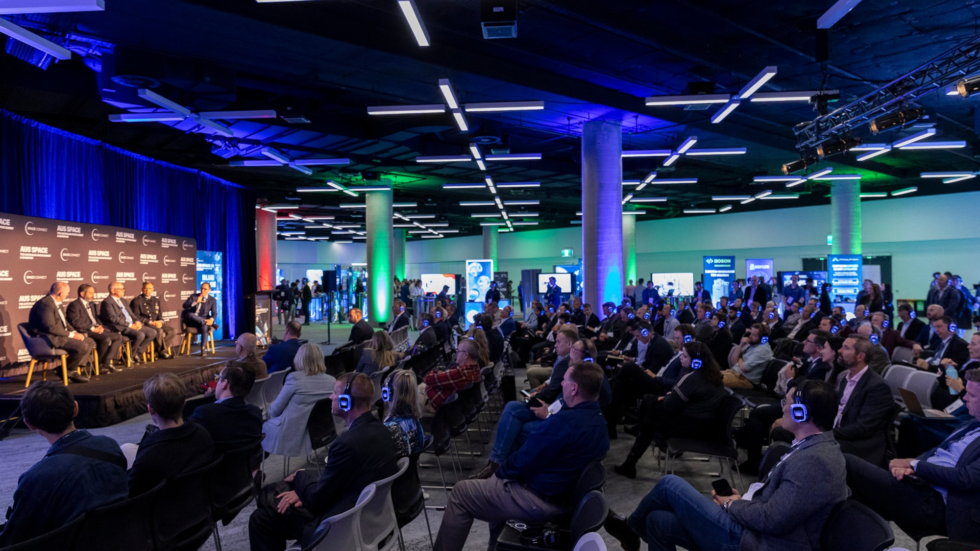 A crowd watches 6 officials talk on stage