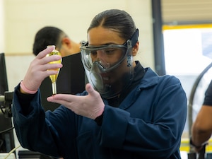 Jannet Diaz, 412th Test Wing Maintenance Group, holds a centrifuge with oil that is part of magnetic particle inspections and explains the procedures the Non-Destructive Inspection team uses to identify potential damage to aircraft at Edwards Air Force Base, California, May 6, 2025. NDI specialists play a role in ensuring the safety of equipment, protecting the lives of aircrew members. (Air Force photo by Daniel Kelley)
