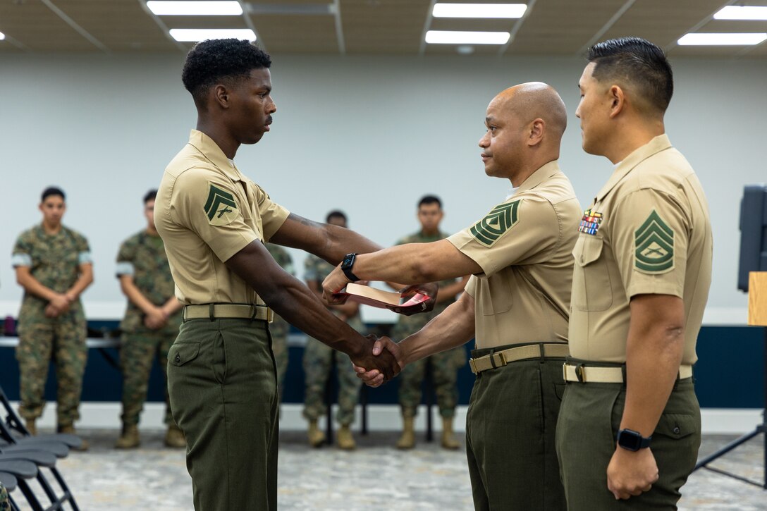 From left, U.S Marine Corps Cpl. Ty’quez Heyward, an administration specialist with the 26th Marine Expeditionary unit, receives a certificate of completion from 1st Sgt. Vabian Elmore Jr., the first sergeant of the 26th MEU and Special Purpose Marine Air-Ground Task Force – Alert Contingency MAGTF (SPMAGTF-ACM) and a native of South Carolina, and Gunnery Sgt. Vincent Song, the radio transmissions chief for the 26th MEU and a native of Virginia, during a Corporal’s Course graduation at Marine Corps Base Camp Lejeune, North Carolina, May 23, 2025. The 26th MEU hosted a Corporal’s Course in order to enhance the leadership skills of Marines and Sailors and help prepare them for the responsibilities of a noncommissioned officer.