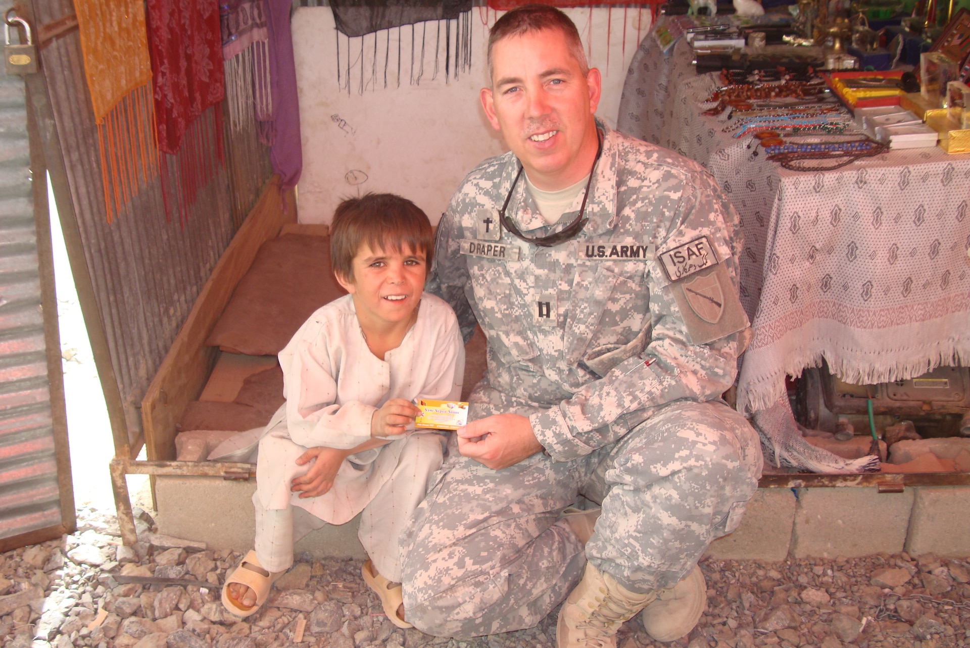 Chaplain (Cpt.) William Draper takes a photo with an Afghan child while he was visiting a local bazar during his deployment to Afghanistan with the 201st Engineer Battalion in 2008-2009.