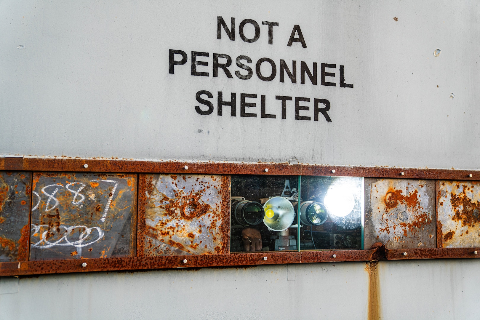 PUMPKIN NECK, Va. — This is not a personnel shelter! It is an armored facility designed to protect high-speed cameras and data acquisition systems from explosions and debris produced by test items. The cameras, along with attached high-power LED lights, are visible through bulletproof glass. Additionally, the other metal panels can be removed or adjusted to create more window space for extra cameras if needed. (Dorina Watermolen/NSWCDD Photo)