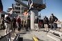 Master of Training Support Vessel (TSV) 5 Vindicator Mike Schoeller, right with hand raised, discusses the ship’s capabilities and TSV operations with Vice Adm. John Gumbleton, commander, Task Force 80 and deputy commander, U.S. Fleet Forces Command, fourth from left, during a fleet visit to Vindicator (TSV 5), assigned to Training Support Vessel Squadron (TSVRON) 4, at Naval Amphibious Base Little Creek, Va., Feb. 24, 2025.