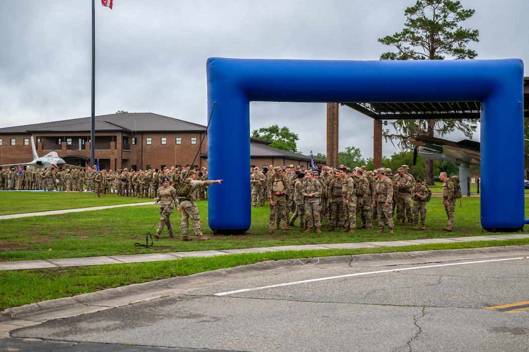 Group of individuals stand under a blown up arch.